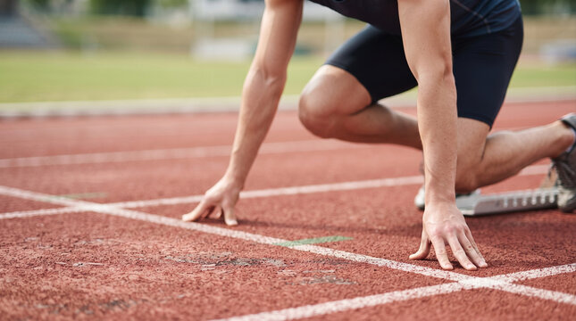 Athlete preparing for a sprint race in a starting position on a professional running track, focused and ready for competition. Dynamic sports concept representing speed, strength, endurance, determina