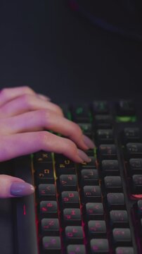 Woman hands with painted nails type on backlit keyboard focusing closely on hand and keys. scene features soft lighting effects around fingers and keycaps emphasizing texture detail in skin
