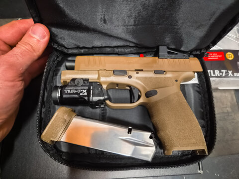 BALTIC STATES - OCTOBER 2, 2026: Springfield Armory Hellcat Pro 9mm semi automatic pistol customized with red dot sight and weapon light in gunsmith workshop