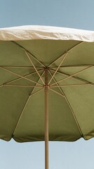 Fototapeta premium Close-up view from below of a light green outdoor patio umbrella with wooden pole against a clear blue sky