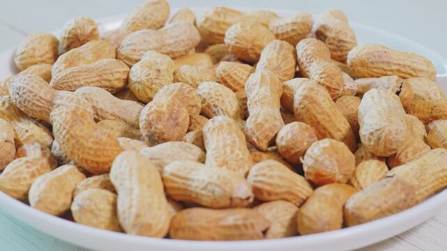 Heap of Whole Raw Roasted Peanuts in Shell on White Plate
