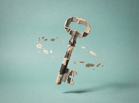 An antique key appears to disintegrate into paper fragments against a pale teal backdrop skeleton metallic brass vintage retro olden historic fragment