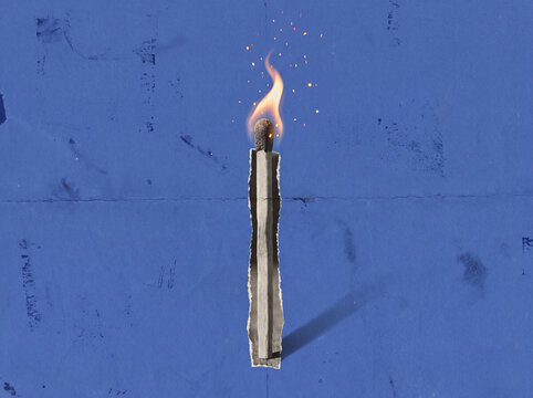 A partially burned matchstick with a flickering flame is displayed against a textured blue background arson burn burning charred combustible combustion consume