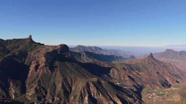 Aerial view of the Gran Canaria summits with Roque Nublo on its plateau, Roque Bentayga on a ridge and Mount Teide on Tenerife faintly visible on the horizon.