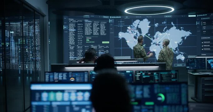 Army Military Surveillance Monitoring Control Room: Two Defense Specialists in Uniform Have a Meeting and Talk Beside a World Map Display, Planning Strategy While Operators Run Ai Data Analysis.