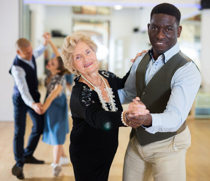 Man and senior woman dancing waltz in studio