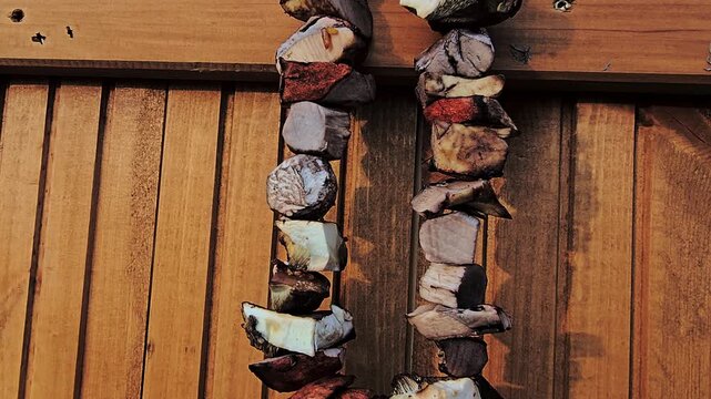 Fresh mushrooms sliced and threaded on a string dry outdoors on a wooden shutter in sunlight for traditional winter storage