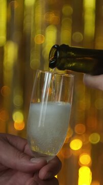 Vertical video. Celebrating New Year, anniversary or birthday. Pouring glass of champagne or sparkling wine at party.