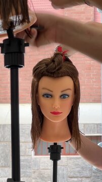 Vertical video featuring a close-up of a professional hairstylist's hands precisely cutting and styling hair in a modern beauty salon