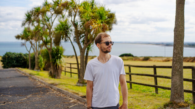Young man looking toward a coastal road and ocean on a sunny day.