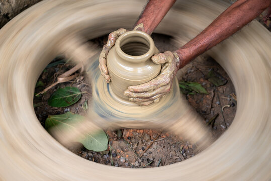 Joypurhat, Rajshahi Division, Bangladesh - 23 September 2026: View of a potter shaping a clay pot on a spinning wheel with hands covered in wet clay.
