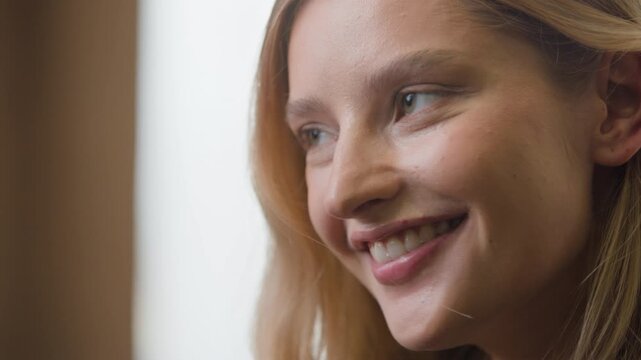Close up Caucasian woman touching face flirty looking at camera smiling enjoy beauty indoors. Female girl with optimistic mood with perfect delicate facial skin soft hair dermatology health feminity