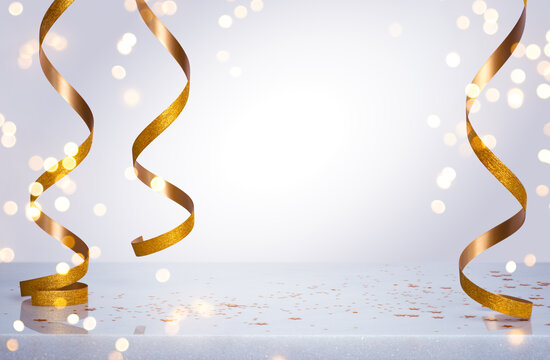 Festive empty table background with golden curling ribbons and abstract bokeh light