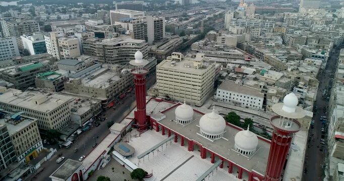 Aerial view of Memon Masjid with its distinctive red minarets and white domes surrounded by the dense urban landscape of Karachi, Sindh, Pakistan.