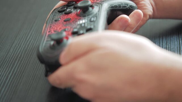 Hands gripping gaming controller on dark wooden surface Technology Concept