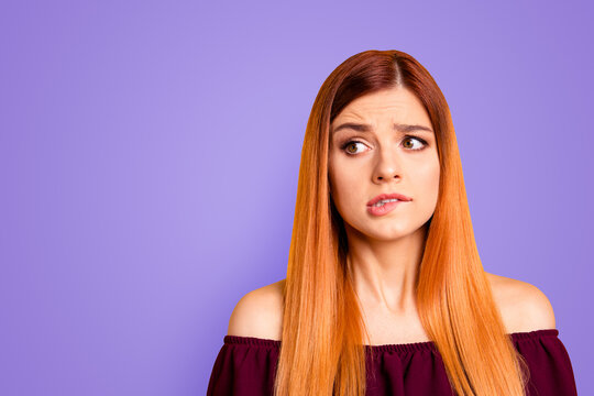 Red straight-haired attractive cute nice scared young girl, biting lip. Copy space. Isolated over bright vivid yellow background