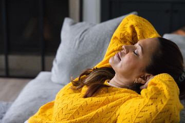 Fototapeta premium Mustard-yellow knit sweater is draping on light-gray sofa in living room, with gray cushion