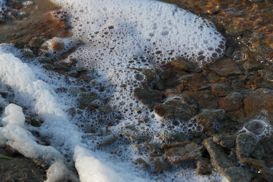 Close-up of waves crashing on the shore with foam