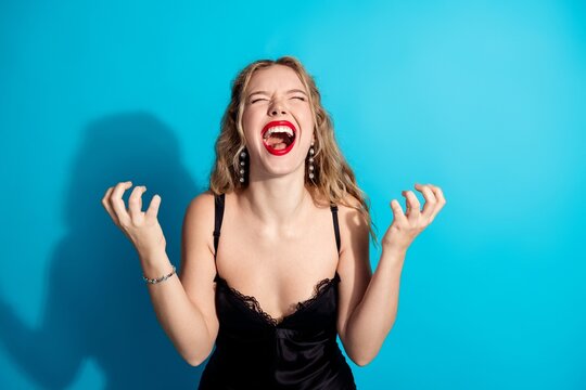 Young woman laughing joyfully with red lipstick against a bright blue background, expressive celebration and carefree fashion portrait