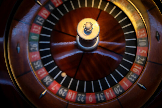 Casino roulette wheel with white ball in slot. Classic gambling equipment with red and black numbers. Close view of wooden game device for luxury betting entertainment.