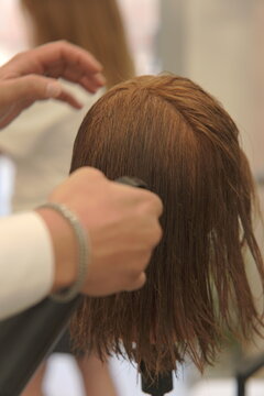 Close-up shot of a professional hairstylist's hands precisely cutting and styling hair in a modern beauty salon
