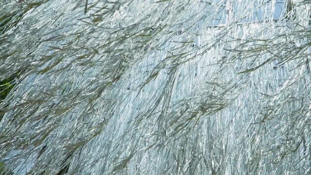 Close-up video of shiny metallic silver foil streamers and shredded tinsel moving in the wind, creating an abstract metallic background with glimmers of light