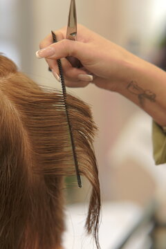 Close-up shot of a professional hairstylist's hands precisely cutting and styling hair in a modern beauty salon