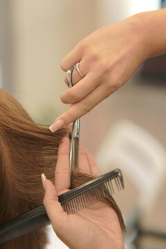 Close-up shot of a professional hairstylist's hands precisely cutting and styling hair in a modern beauty salon