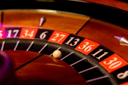 Casino roulette wheel with white ball stopped on black number thirteen slot. Vintage gambling device features lucky thirteen pocket. Close view captures betting game.