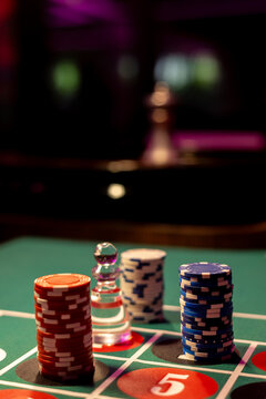 Clear glass roulette dolly marker stands with stacks of casino chips on green felt table. Vertical low angle view captures gambling layout with copy space above.