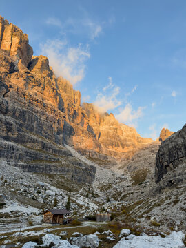 Tramonto sulle pareti delle Dolomiti di Brenta dal Rifugio Brentei con baita in legno