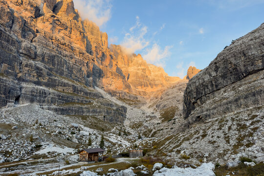 Tramonto sulle pareti delle Dolomiti di Brenta dal Rifugio Brentei con baita in legno