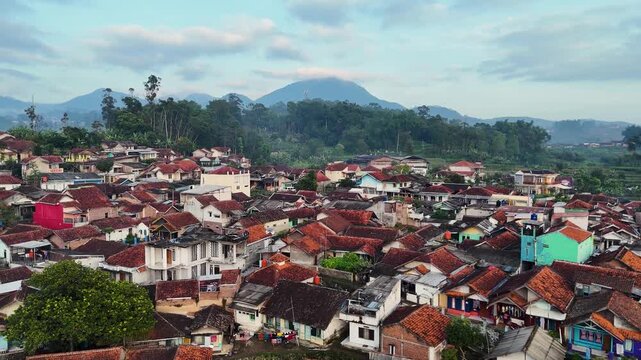 Aerial view of the Ciwidey residential area featuring dense red-tiled rooftops nestled among lush green hills in Bandung, West Java, Indonesia.