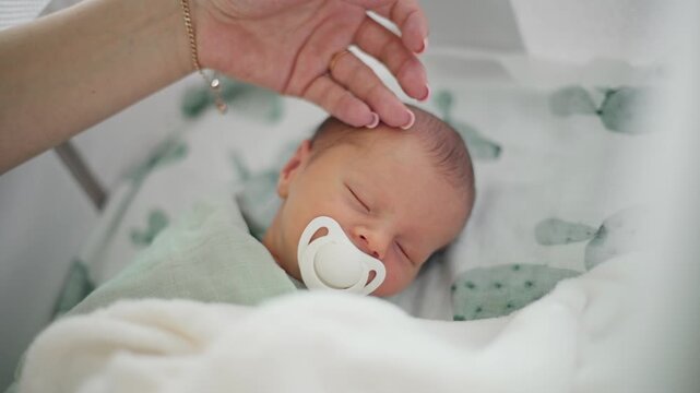 Mom Gently Strokes Newborn Baby Boy Sleeping In The Crib