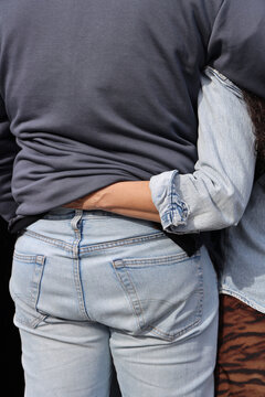 back rear view of woman wrapping arms around partner, gently gesturing, woman touch touching male back under shirt. middle aged MAN WEARING blue jeans shirt with pockets Close up image photo