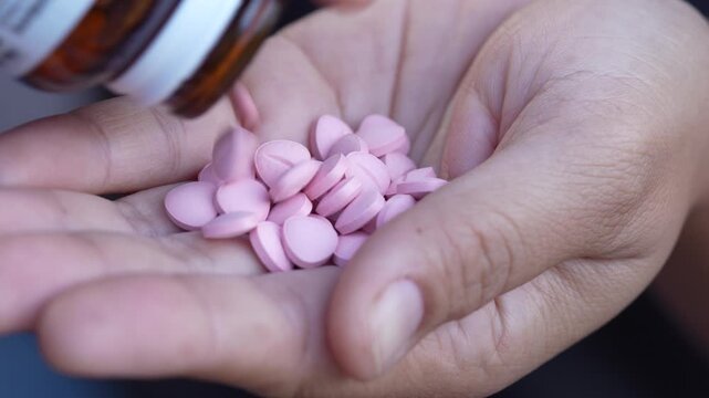 close up woman hand holding a medicine, with pours the pills out of medicine bottle. Stop drug use Taking Medication Caring for the health care medical concept.