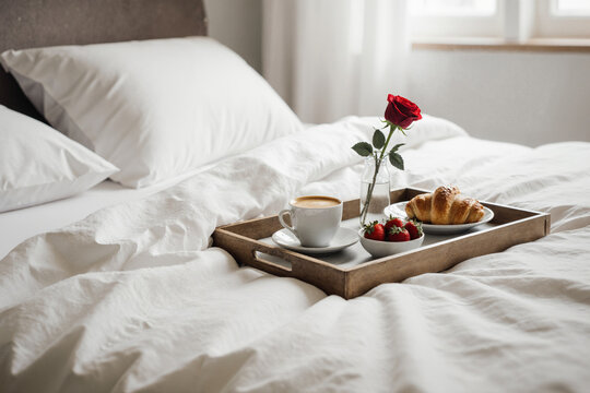 Valentine's breakfast in bed with coffee, croissant, strawberries and a rose