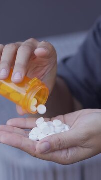 close up woman hand holding a medicine, with pours the pills out of the yellow orange medicine bottle. Stop drug use Taking Medication Caring for the health care medical concept.