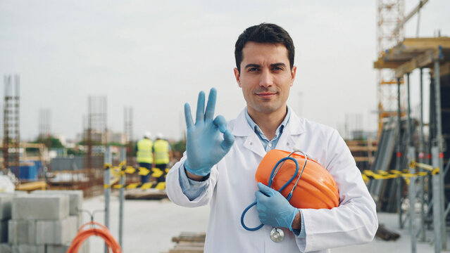 engineer showing okay sign holding hard hat at construction site