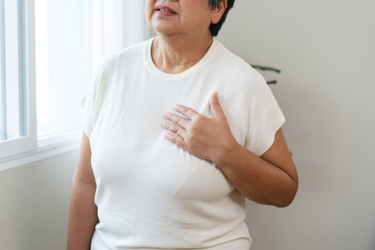 Asian elderly grabbing her chest and feeling pain from heart attack suddenly at home.