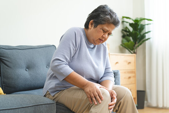 Arthritis is a chronic disease problem in elderly healthcare, Asian old female touching her leg feeling pain in her knee joint, and can't walk properly because of inflammation and pain