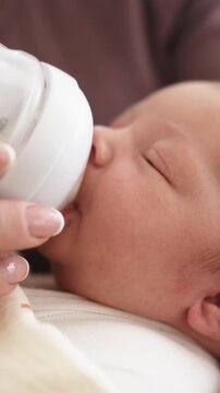 Mom Holds Wrapped Baby While Feeding From Bottle In Bright Room. Relaxed And Nurturing Moment., Vertical Video, Vertical Video