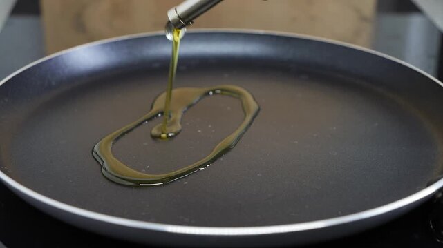 Olive oil being poured into an empty frying pan, ready for cooking. Culinary preparation and cooking process concepts. High quality 4k footage