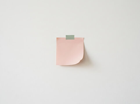 Blank pink sticky note taped to a wall