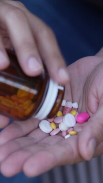 close up man hand holding a medicine, with pours the pills out of medicine bottle. Stop drug use Taking Medication Caring for the health care medical concept.