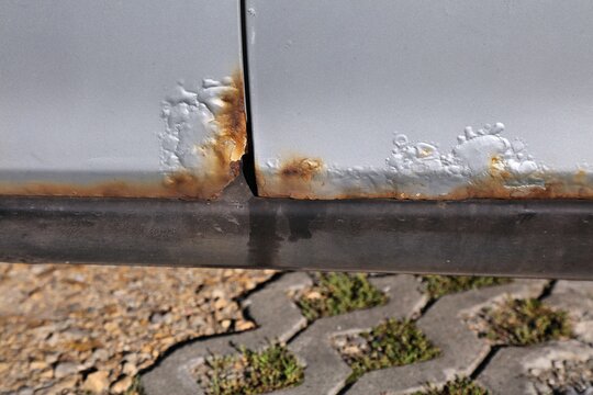 Rusting door in an old car. Weather damage in vehicle.