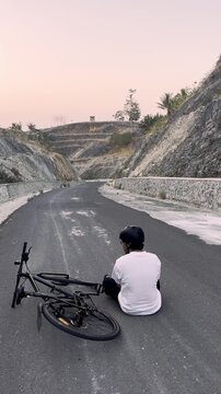 Cyclist Resting on Road in Scenic Landscape