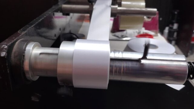 Industrial machine printing and rolling garment care labels in textile factory
