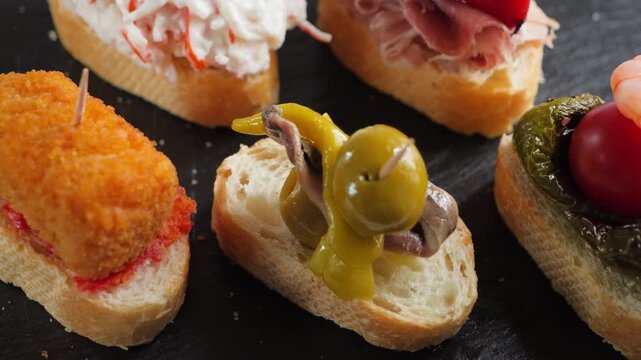 Assorted Spanish pintxos with croquettes, shrimp, olives, tomato, padron pepper and toppings on bread skewers. High quality 4k footage