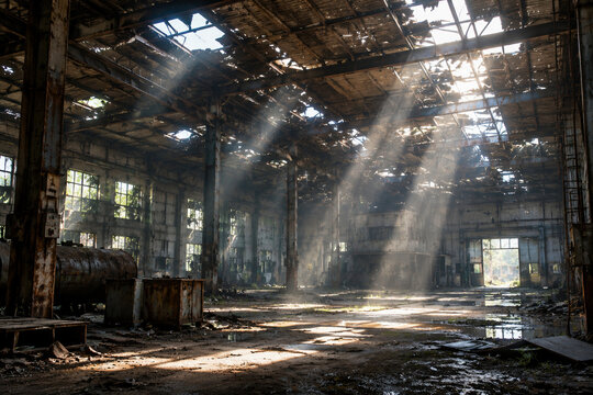 Interior of abandoned industrial building with sunlight through roof.